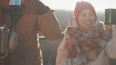 friends toasting with hot drinks outdoors in winter