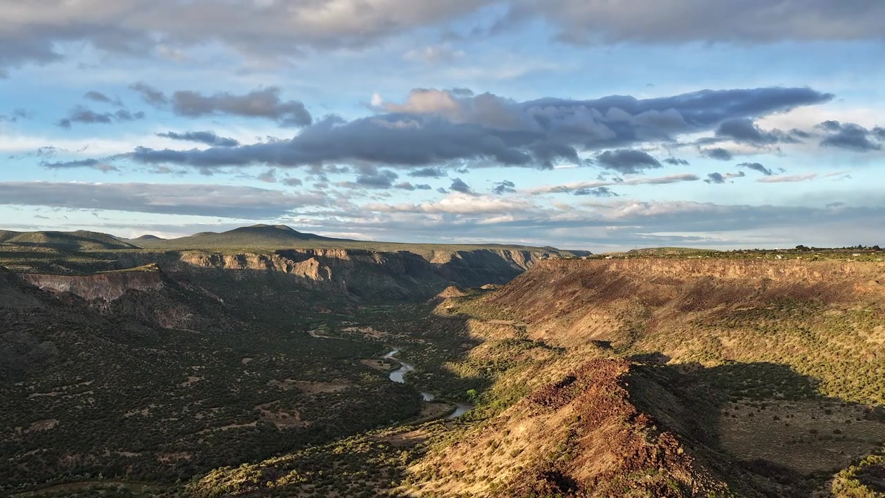 Timelapse professionale con drone che mostra il fiume Rio Grande che scorre attraverso una valle profonda. Movimenti cinematografici delle nuvole proiettano ombre mutevoli sull'aspro altopiano sudoccidentale e sulla gola del fiume