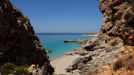 Secret-beach-on-quiet-seaside-of-Mediterranean-seen-through-cliffs-on-shore,-blue-turquoise-sea-water-of-shallow-lagoon