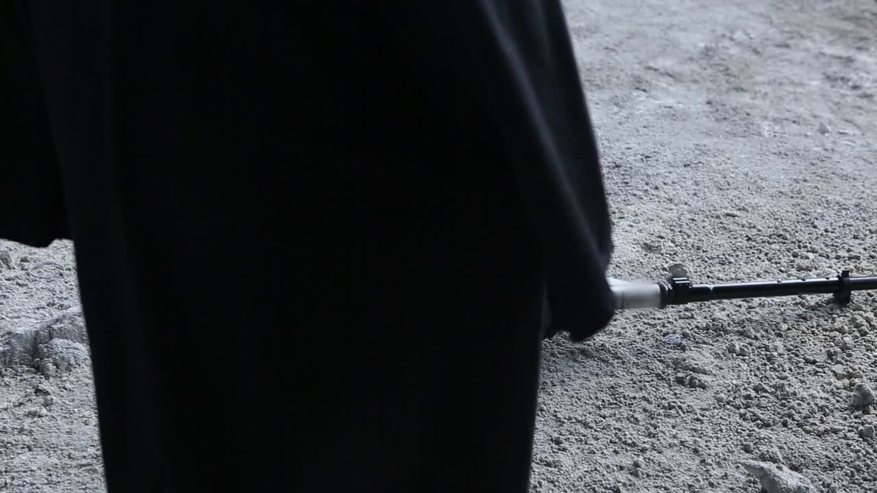 Mysterious person in black mantle with child skooter an abandoned zone in day