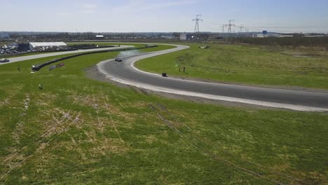 wide aerial shot of a drifting car on a race track with smoking tires and sunny weather