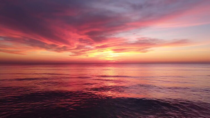 Vibrant pink and orange sunset over calm ocean waves