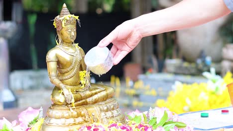 sequential pouring of water over a golden buddha statue