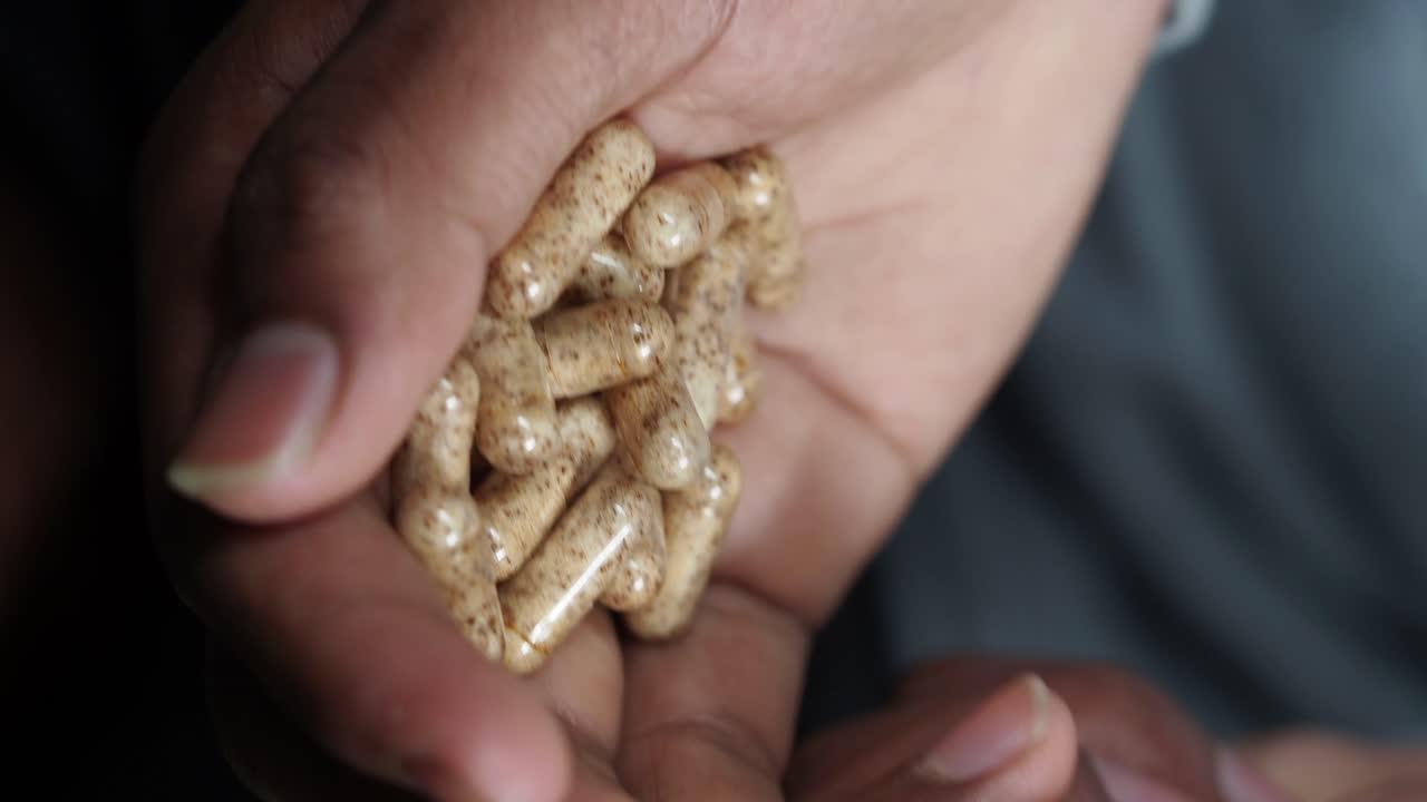 Hands holding a pile of capsules