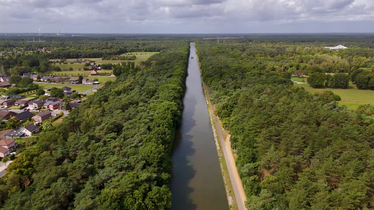 Aerial view of a canal lined with trees next to a village