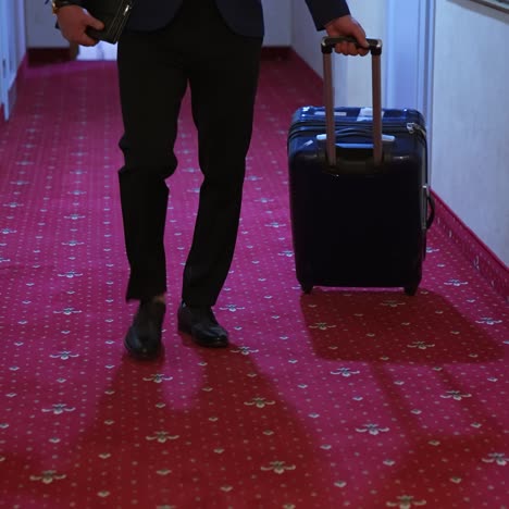 businessman in hotel corridor with suitcase