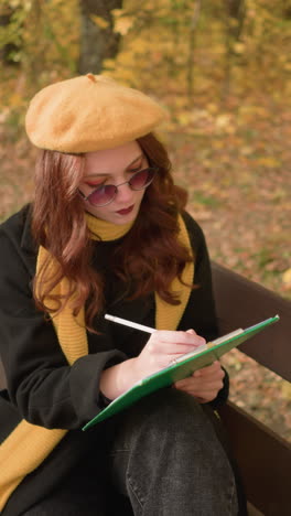 creative mind thoughtfully sketching on canvas, seated with head tilted to the left on wooden park bench, immersed in artistic expression, dressed in yellow beret and scarf