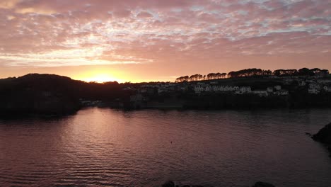 Sweeping-drone-shot-of-Fowey-Harbour-at-sunset,-showcasing-idyllic-views-and-peaceful-ambiance