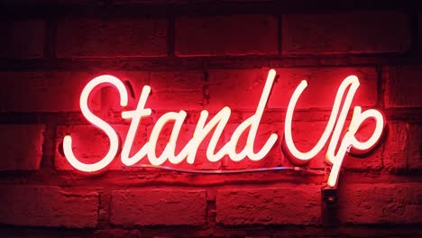 flickering neon sign with stand up illuminates a red brick wall, creating a vibrant atmosphere for comedy and entertainment