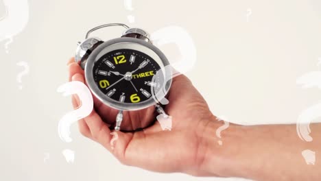 animation of question marks over caucasian man holding alarm clock ticking on white background