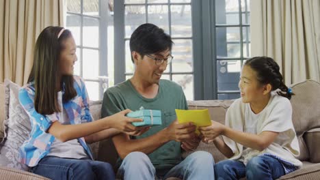 father receiving greeting card and gift box from siblings in living room 4k