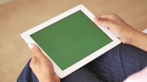 mujer sosteniendo una tableta con una pantalla verde