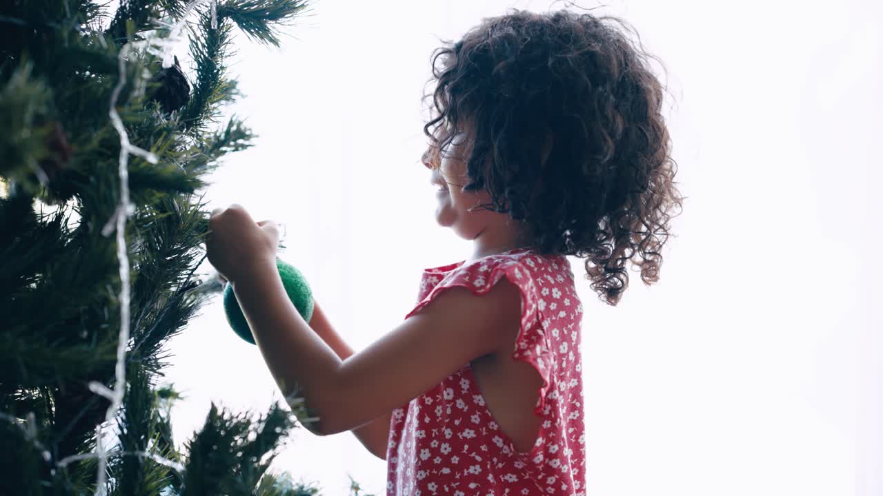 Young Girl Decorating Christmas Tree with Green Ornament