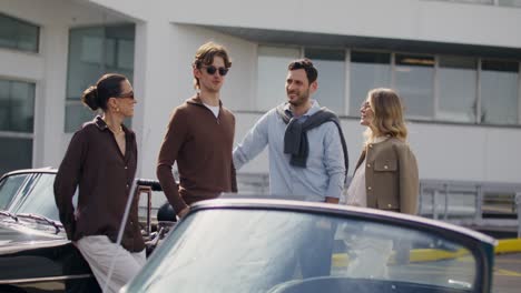 friends talking outdoors near classic cars