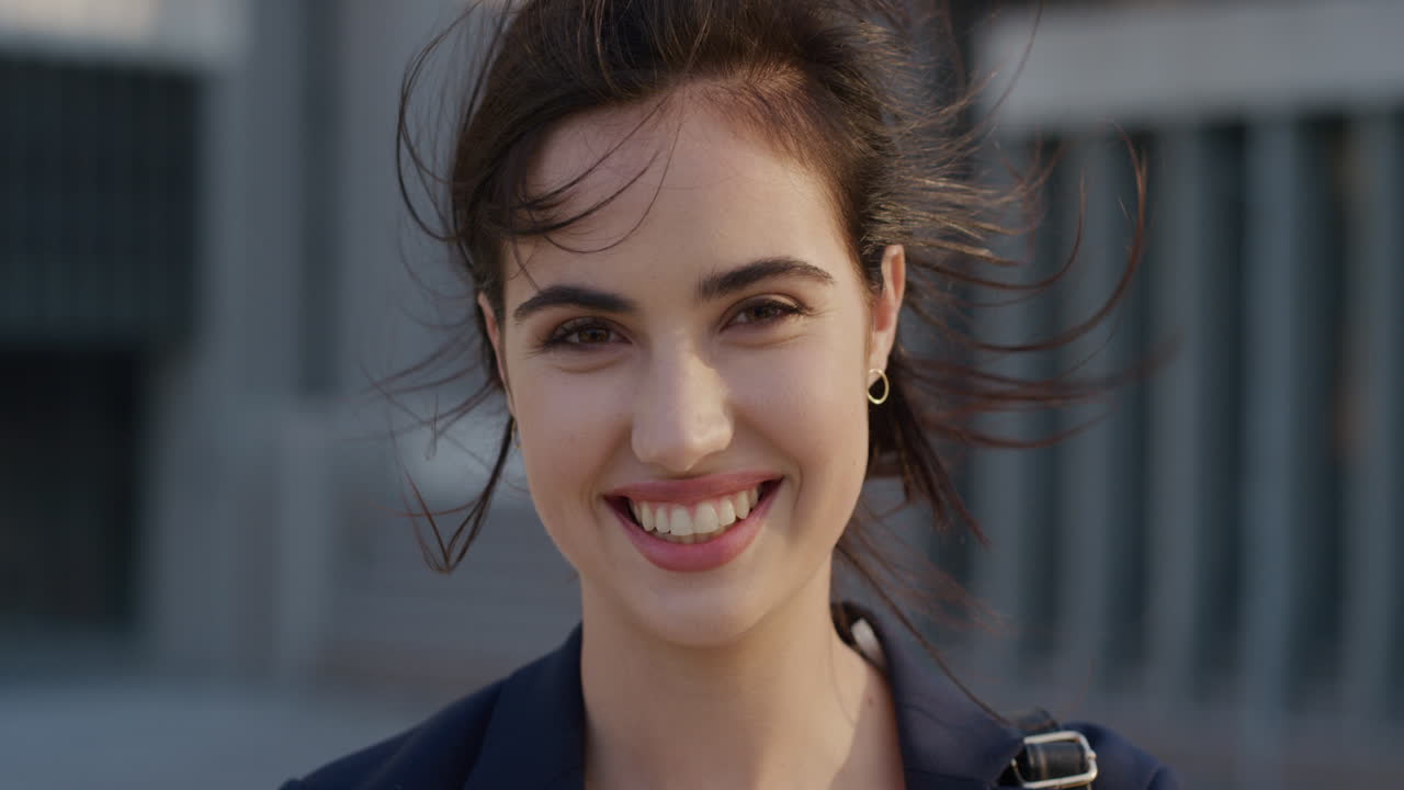 retrato feliz joven mujer de negocios sonriendo corriendo mano a través del cabello disfrutando de estilo de vida urbano profesional viajera femenina en la ciudad el viento soplando el cabello