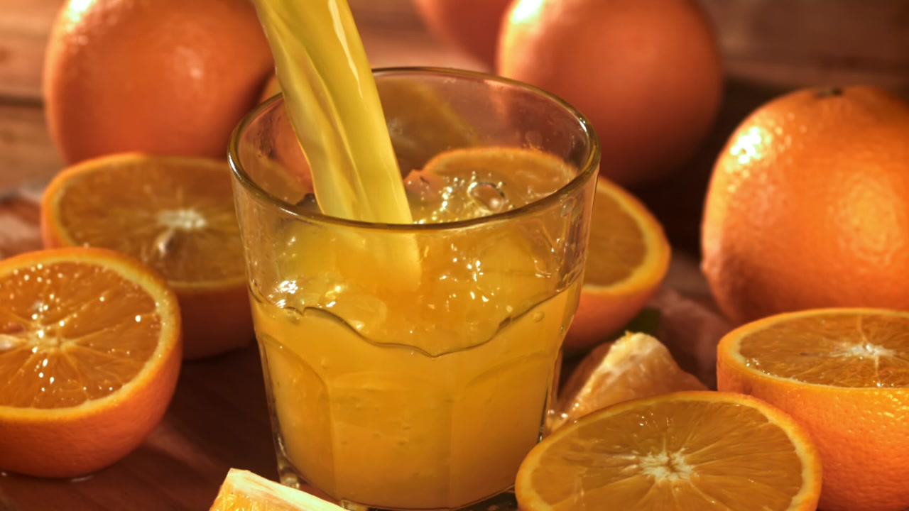 Vibrant Orange Juice Poured into Glass with Fresh Oranges