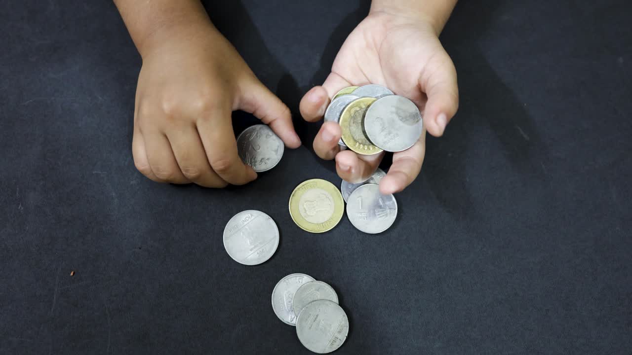 Small hand interacting with Indian coins illustrating growth in money handling skills