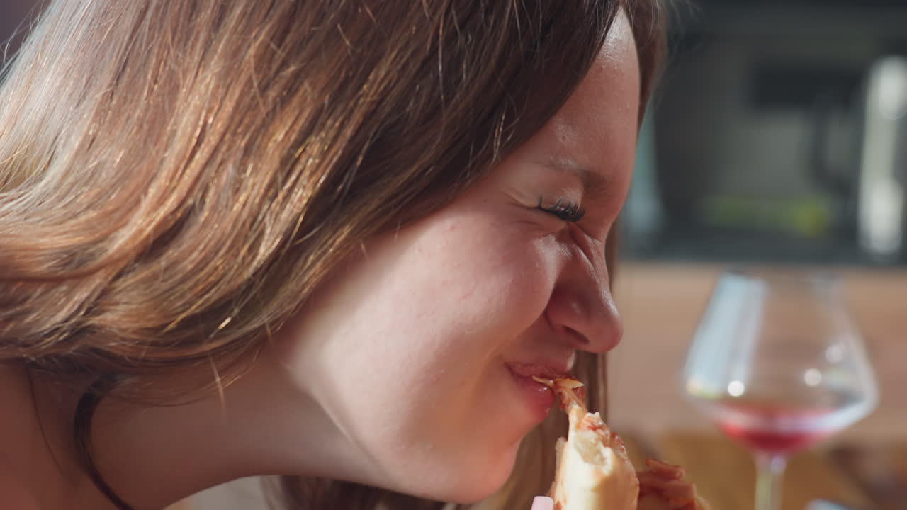 Close up of lady eating a slice of pepperoni pizza, savoring the delicious flavor, the focus is on her enjoying the pizza, with a bite being taken and a joyful expression