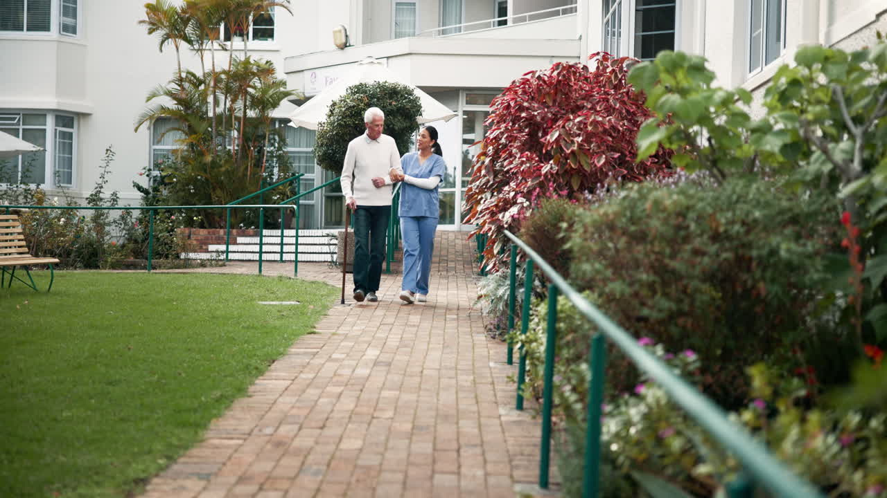 Caregiver assisting senior man walking in garden
