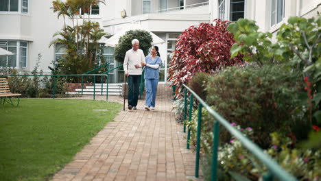caregiver assisting senior man walking in garden