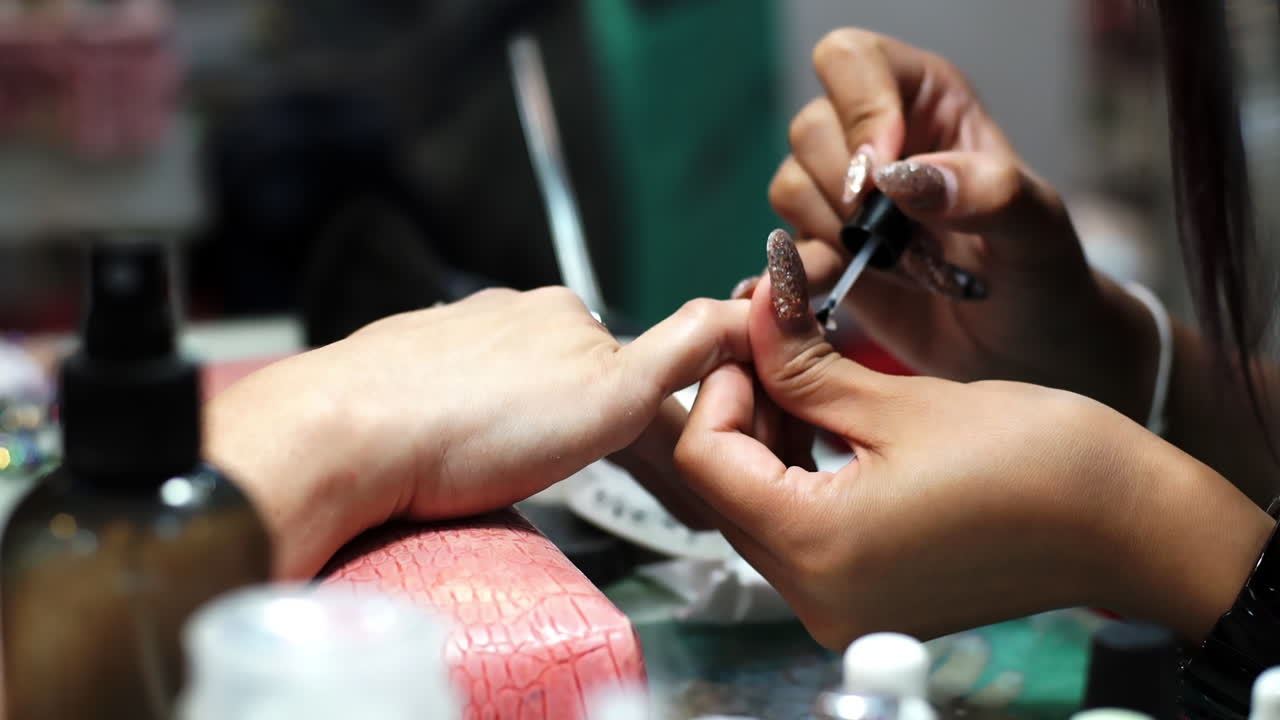 Close-up of a woman receiving a professional hand and nail manicure at a beauty salon. Focus on female hands, skincare, and nail care treatment