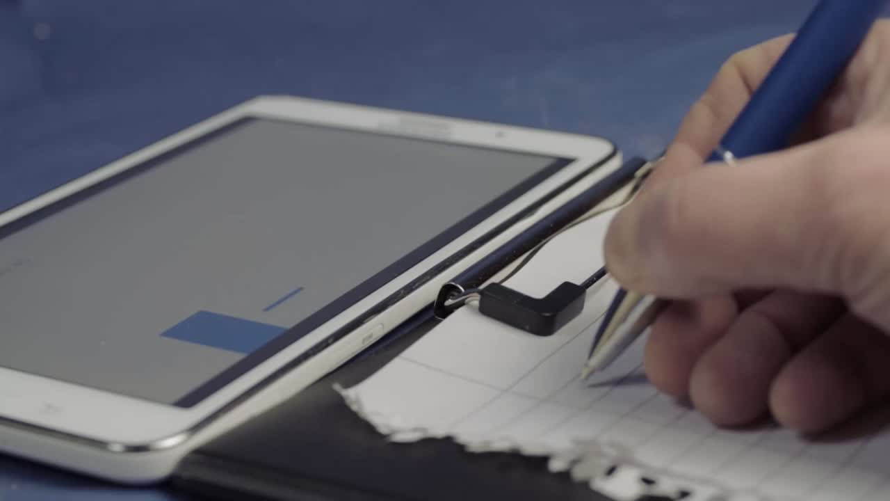 Writing sales report on clipboard with blue graph in background medium shot