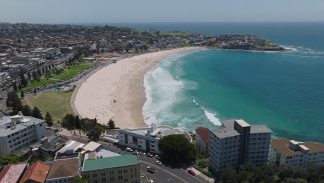 Above-drone-shot:-the-expanse-of-Bondi-Beach,-one-of-Australia's-coastal-jewels,-with-sunbathers-like-ants-on-the-golden-sands-near-the-azure-sea