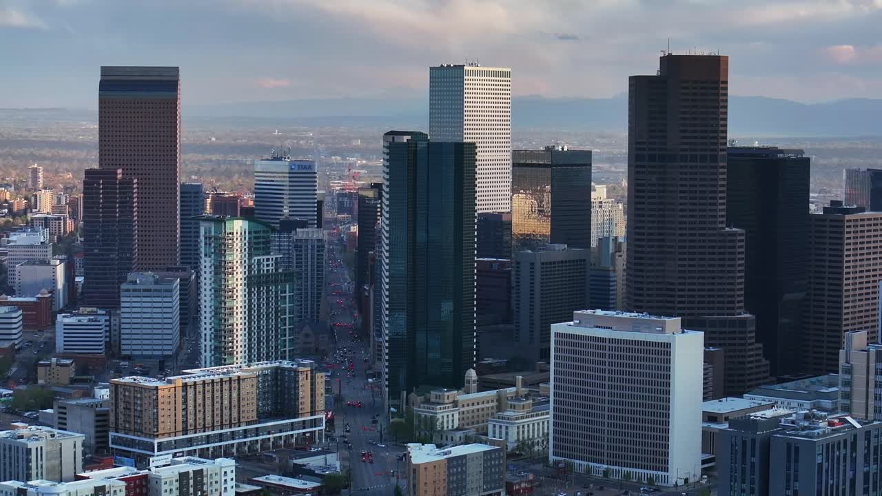 Downtown Denver cityscape city tall skyscraper buildings aerial drone Colorado spring summer afternoon sunset mountains range landscape City Park Rhino pan clouds sunny panorama parallax right motion