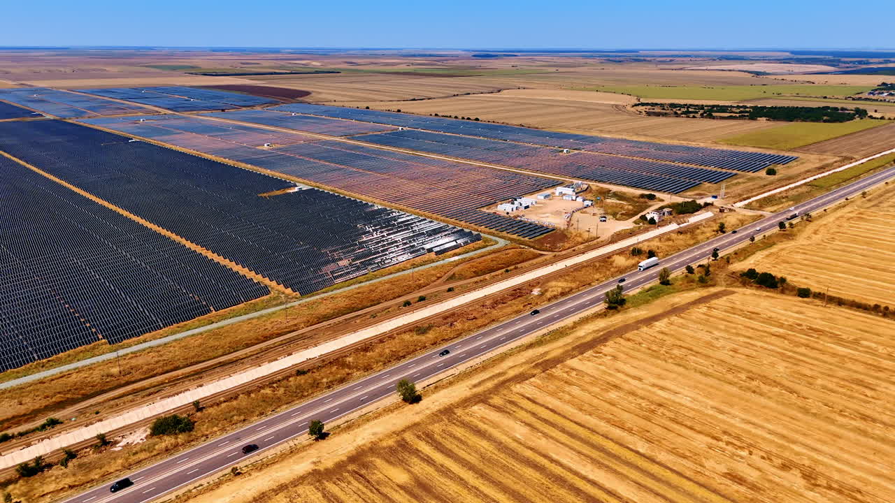 Solar panels blanket the countryside. Solar panels span vast fields beside a highway, highlighting renewable energy efforts in the countryside