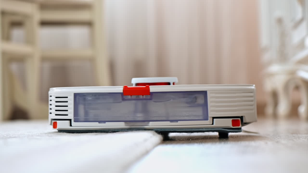 Working robotic vacuum cleaner at home, partly moving on a carpet