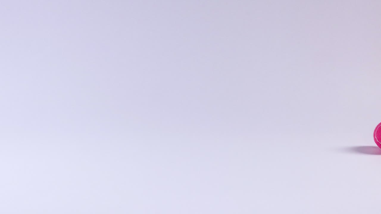 una pelota de tenis rosa rodando a través de una superficie