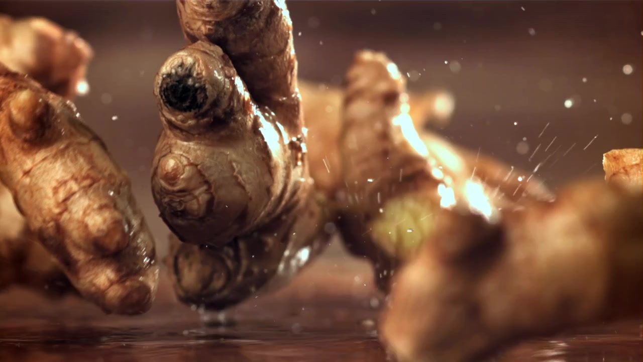 Fresh Ginger Roots Falling and Splashing into Water