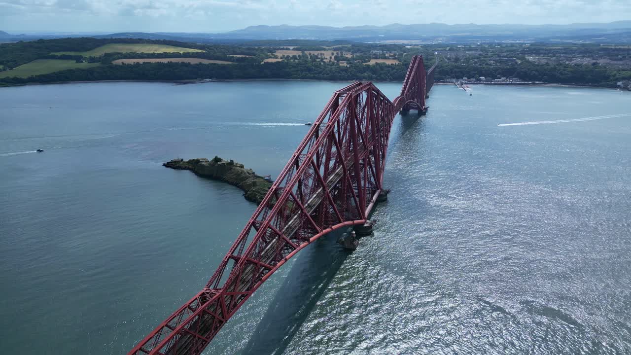 Stunning 4K drone shot of the iconic red steel Forth Bridge in Scotland, showcasing its engineering marvel and breathtaking aerial views over the river and surrounding coastline.