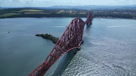 Stunning 4K drone shot of the iconic red steel Forth Bridge in Scotland, showcasing its engineering marvel and breathtaking aerial views over the river and surrounding coastline.