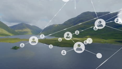 Animation-of-connected-icons-over-aerial-view-of-lake-between-mountains-against-cloudy-sky