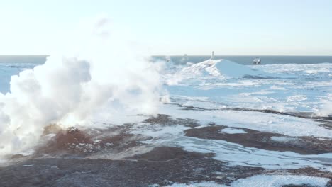 white gas from gunnuhver geyser with distant reykjanesviti lighthouse