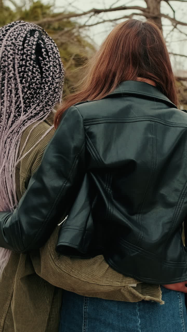 Two Young Women Embracing Outdoors, Seen from Behind