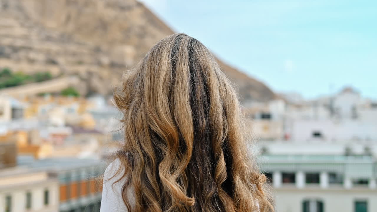 Caucasian woman watching a panoramic view of the town Alicante in Spain. Town Hall in the background
