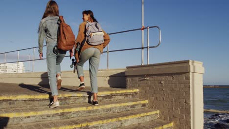 rear view of a caucasian and a mixed race girl walking seaside