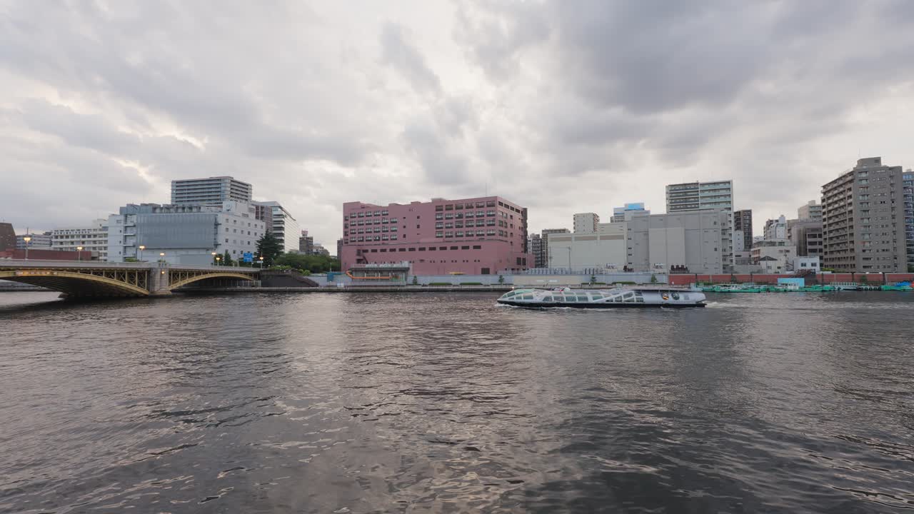 Tourist boats move down the Sumida River at dusk. A dynamic scene of Tokyo's riverside