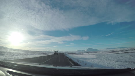 perspective from the windshield on a road trip passing other vehicles through the snowy icelandic mountains