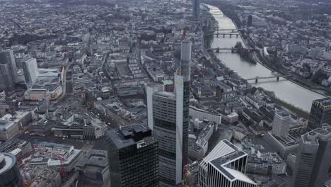 elevated footage of tall modern office building. tilt up reveal of city panorama. frankfurt am main, germany