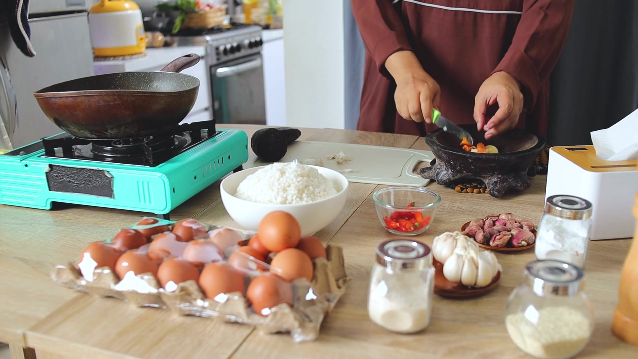 Menyiapkan bahan-bahan segar dan rempah-rempah untuk nasi goreng kuning buatan sendiri dengan peralatan dapur tradisional