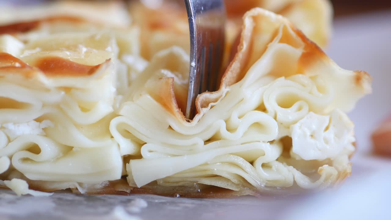 Close-up of a delicious Turkish pastry, likely a type of baklava or börek, being eaten with a fork.
