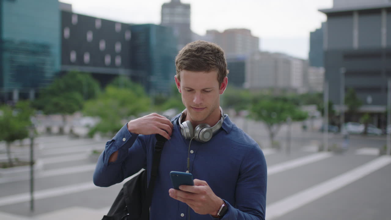 매력적인 젊은 남자 학생의 초상화 대학 캠퍼스에서 스마트 폰 앱을 사용하여 소셜 미디어를 검색하고 도시 생활 방식을 즐기는 문자 메시지