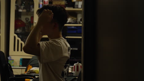 Asiatischer-Mann-Glättet-Sein-Haar,-Während-Er-In-Seinem-Zimmer-Spiegelt,-Hongkong