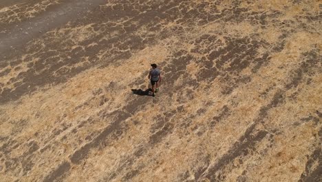 person running through arid brown field from aerial view with drone