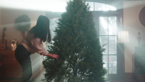 woman decorating a christmas tree with sunlight rays