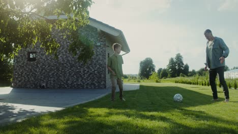 father and son playing soccer in the backyard