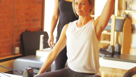 Female-trainer-assisting-woman-with-exercise